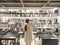 Rear view of Woman shopping for a chair in furniture store. Chairs on display shelf with white tone light.