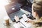 Rear view.Woman is sitting at table,working on laptop with inscription on screen e-learning,image of square academic cap