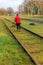 Rear view of woman walking with her dog between disused train track rails