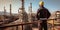 Rear view of a worker at the top of an oil refinery, looking out over the complex network of pipes and tanks , concept