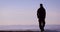 Rear view of a young adult man, traveller walking in the mountains, enjoys the beautiful view on mountain ridges in morning light