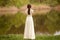 Rear view of a young anonymous bride in a beautiful full wedding dress, with hairstyle, looking down, nature background.