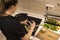 Rear view of a young beautiful girl cooking and preparing vegetarian food in her kitchen alone. Swedish woman grinding pepper into