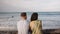 Rear view of young couple looking at view and pointing at sea from beach