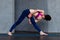 Rear view of young female yogi in sports bra and leggings doing bound extended side angle pose, baddha utthita