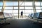 Rear view. Young man holding smartphone in hands while standing in airport terminal