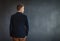 Rear view of young man standing against grey wall background