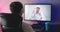Rear view of young man watching video online conference with doctor. Alone patient man is consulting with physician at