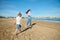 Rear view of young mother and her daughter, playing together on the beach, running and leaving footsteps on the wet sand