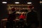 Rear view on young parents and their little child in santa hat. Family sitting at the table in a room with bright garlands. Merry