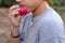 Rear view of young romantic man is holding a red rose in his mouth on nature blurred background. Love and romance Valentine`s day