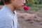 Rear view of young romantic man is holding a red rose in his mouth on nature blurred background. Love and romance Valentine`s day