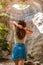 Rear view of a young woman adventurer standing in an underground cave with an opening to the outside, Sunlight through a cave