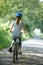 Rear View Of Young Woman Cycling On Country Lane