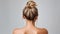 Rear view of young woman elegant bun hairstyle, grey background, copy space