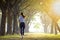 Rear view of young woman running in the forest on  foggy at  morning