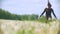 Rear view of young woman running from the meadow of dandelions in sunny day