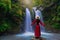 Rear view of young woman standing in front of waterfall with her hands raised at Sapan Waterfall, Khun Nan National Park, Boklua