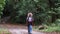 Rear view of young woman tourist trekker with backpack walking in autumn forest. Active healthy lifestyle.