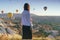 Rear View Of A Young Woman Watching Ballooning Festival At Sunrise