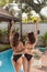 rear view of young women in bikini and swimsuit at poolside of hotel