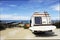 Rear of vintage camper parked on the beach seaside with a surfboard on back - Leisure trip in the summer