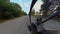 Rear wheel view of MTB bicycle. Bicyclist rides mountain bike along unpaved dirt sandy road in forest at sunset. Chain