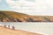 Rear Wide Angle View Of Multi-Generation Family Walking Along Shore On Winter Beach Vacation