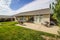 Rear Yard  Of Ranch Home With Concrete Patio With Lounge Chairs & Bench