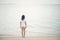 Rear of young woman standing on the beach with barefoot.