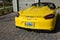 The rearend of a yellow Porsche Spyder sitting in front of a home