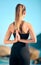 Rearview beautiful woman practising yoga exercise on the beach. Young female athlete stretching while working out