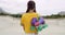 Rearview of a female roller skater carrying skates in a skate park. A cool urban skater from behind with retro purple