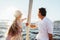 Rearview of two mature people sitting on a sailboat bow and enjoying summer