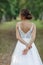 Rearview vertical portrait shiny, calm, mysterious bride with hair bun in glossy lace wedding dress with crossed hands