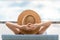 Rearview of woman in sun hat relaxing at luxury hotel tropical resort swimming pool