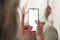 Rearview of a young woman holding a mobile phone with blank white screen sitting at home during the lockdown. Mockup image of a