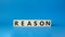 Reason symbol. Concept word Reason on wooden cubes. Beautiful blue background. Business and Reason concept. Copy space