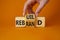 Rebuild and Rebrand symbol. Businessman hand turns wooden cubes and changes the word to Rebrand to Rebuild. Beautiful orange