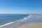 Receding tide on beach at Tybee Island Georgia, USA, distant walkers and beachcombers, blue sky reflected in the water