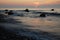 Receding waves roll over a rocky shore at sunrise