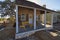 A recently constructed Wooden Old Style house, with a porch with yellow seats and tables in Round Top.