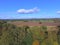 Recently harvested farmland under blue skies with the farm house in the distance and forest drone imagery