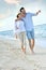 Recently married couple walking on the beach at sunset