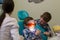 Reception at the dentistry. A little boy lays on the couch with glasses on, his brother holding the lamp