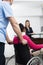 Receptionist Looking At Doctor Pushing Patient On Wheelchair