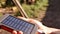 A rechargeable mobile power pack with solar panels in young female traveler's hands, close-up. Connected to and charging a