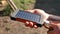 A rechargeable mobile power pack with solar panels in young female traveler`s hands, close-up. Connected to and charging a mobile,