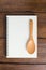 Recipe notebook, spoon on wooden background