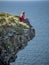 Reckless woman sitting on the edge of a cliff at the Irish west coast